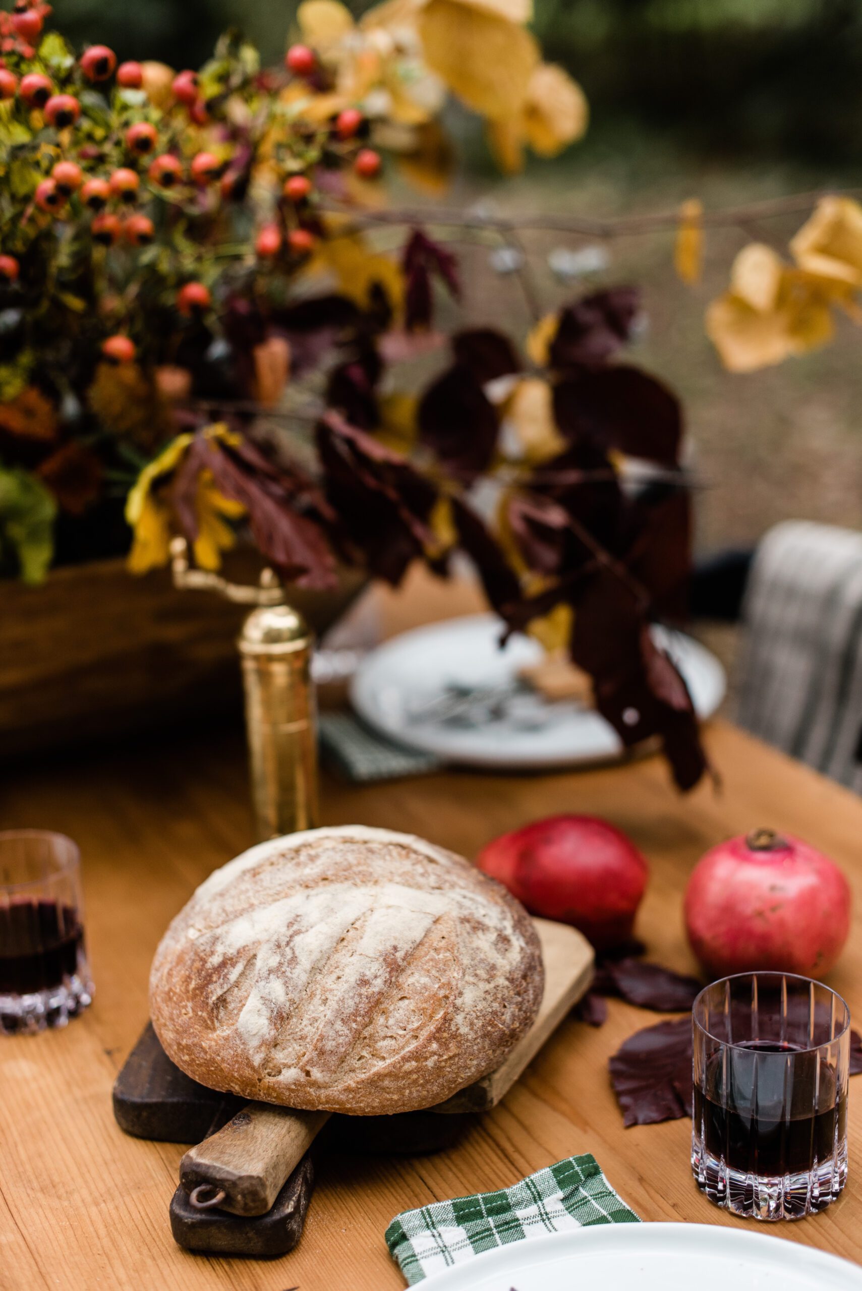 autumn dinner table with rustic bread, pomegranates and wood accents