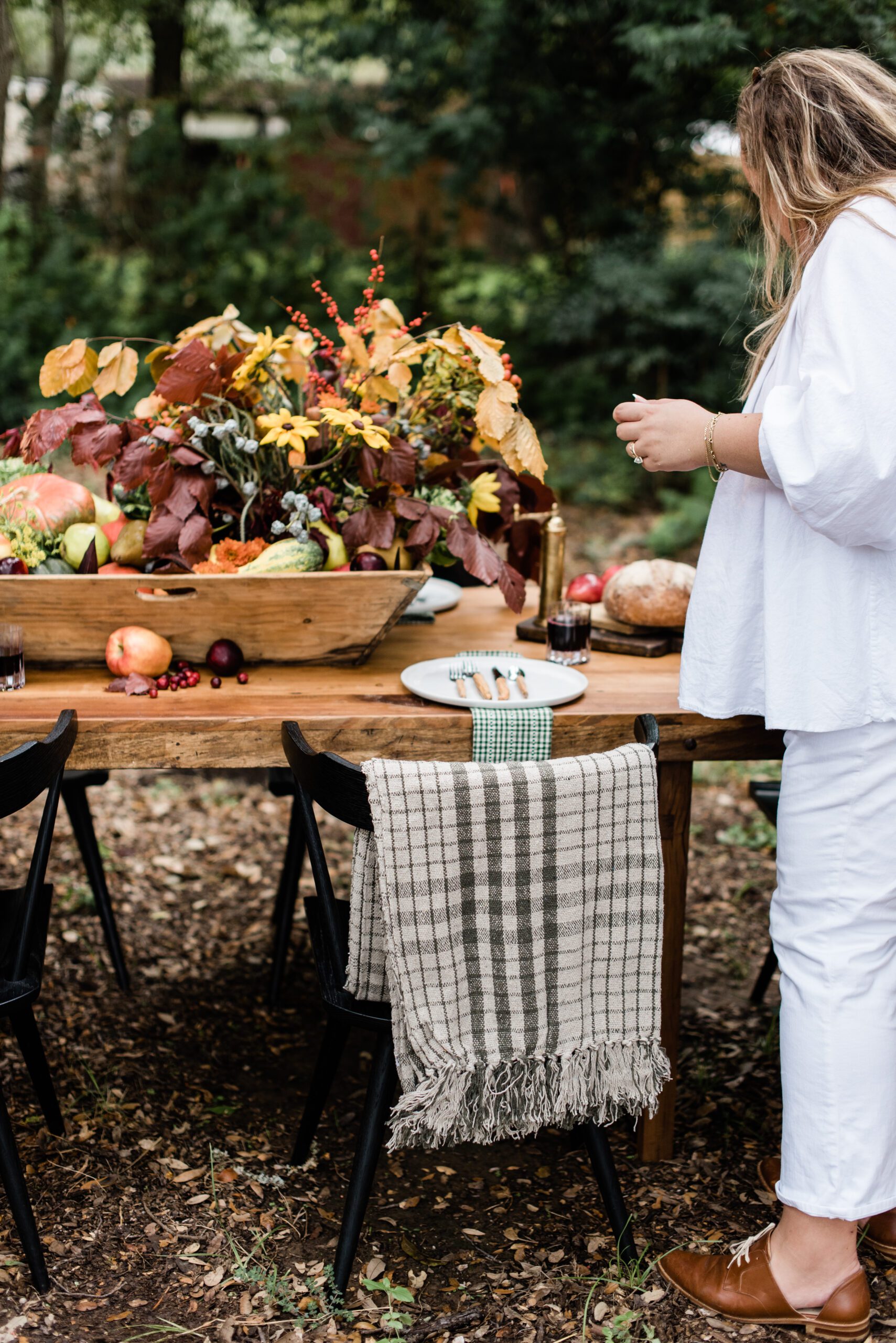 a cozy outdoor table designed with fall foliage, fruits, and vegatables and cozy linens