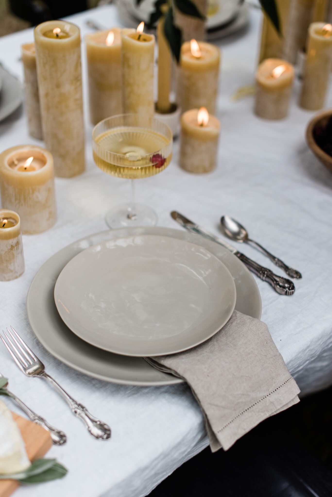 elegant place setting with beeswax candle centerpiece, linen napkins and stoneware plates