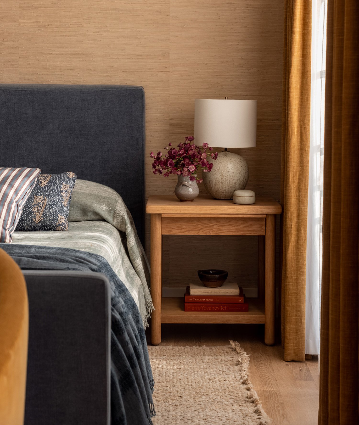 designer oak nightstand with blue upholstered bed