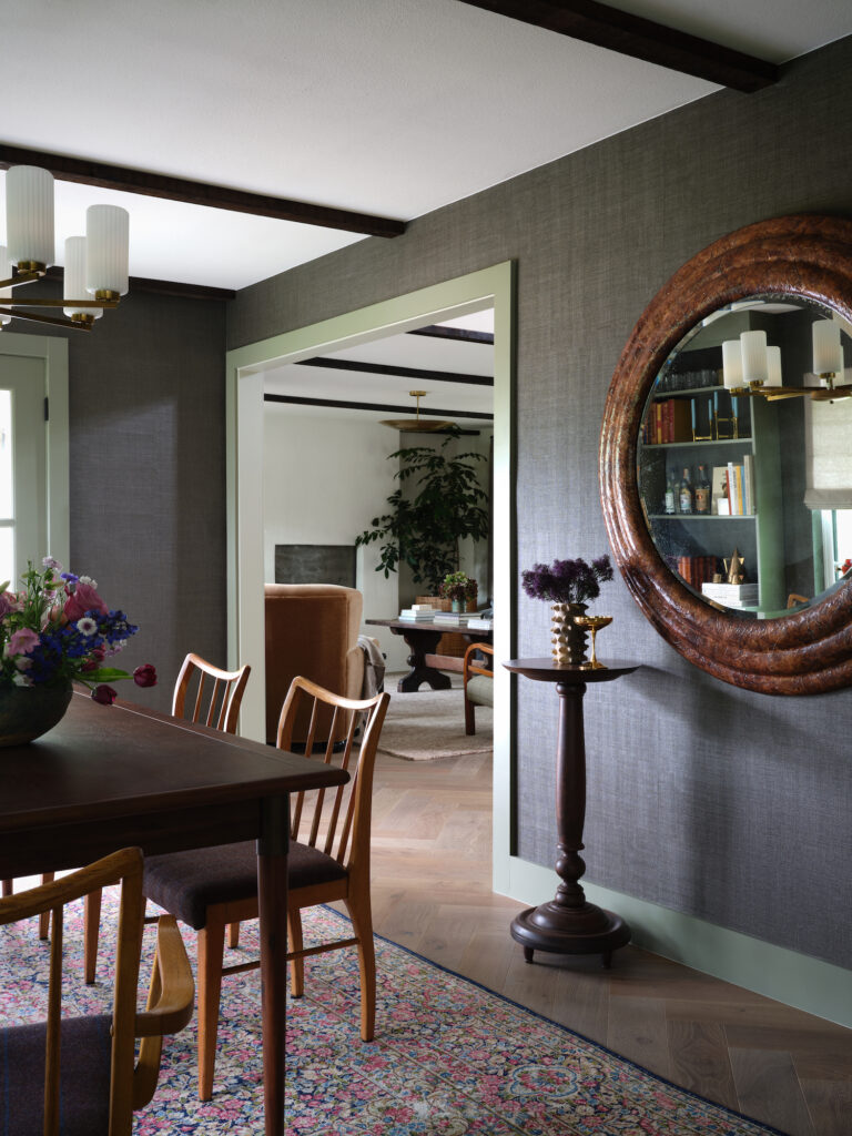 moody Tudor dining room with giant leather mirror and dark wallpaper