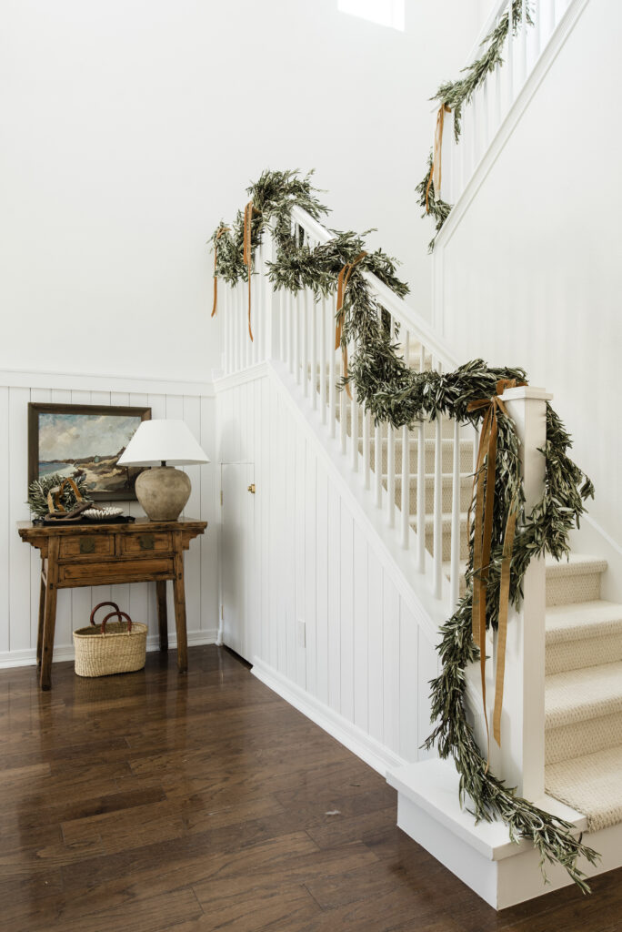 olive leaf garland with copper velvet ribbon lining the stairway holiday decor ideas