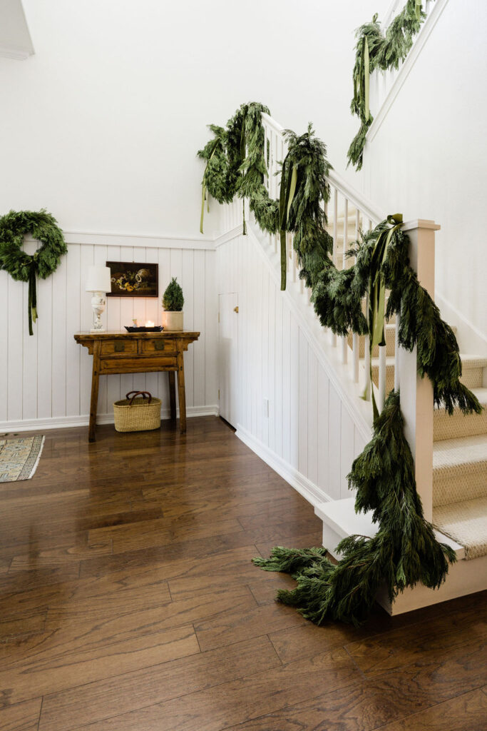 Fresh cypress garland on banister with green ribbons holiday home decor