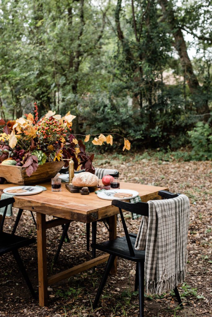 casual Thanksgiving table with fall flowers , fruit and vegetable centerpiece and cozy blankets at each place setting