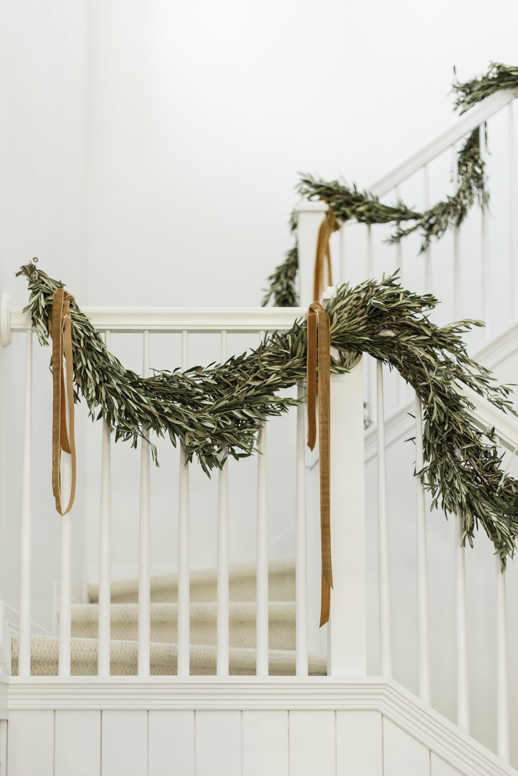 olive leaf garland decorating the stairway with velvet ribbon