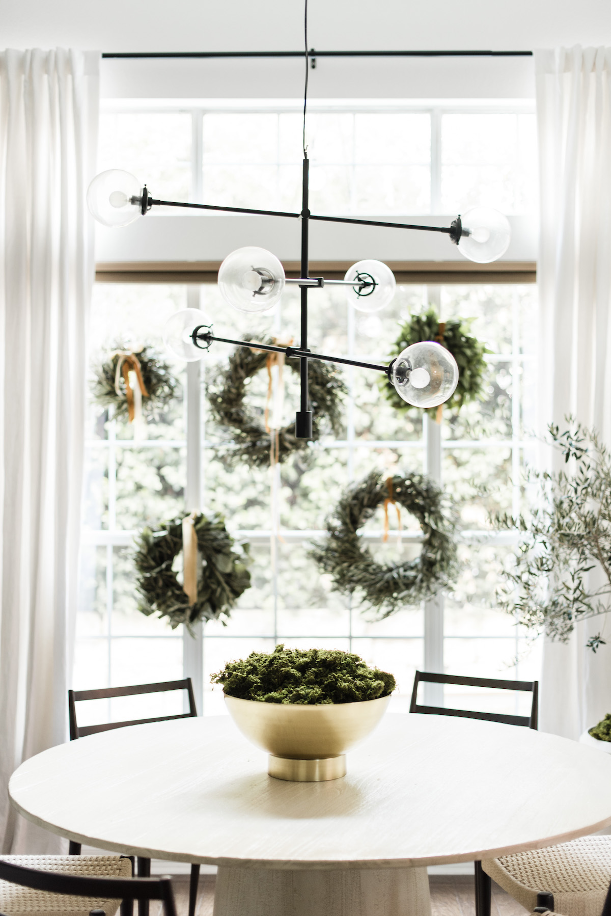 a cluster of natural green wreaths in the window for holiday decor