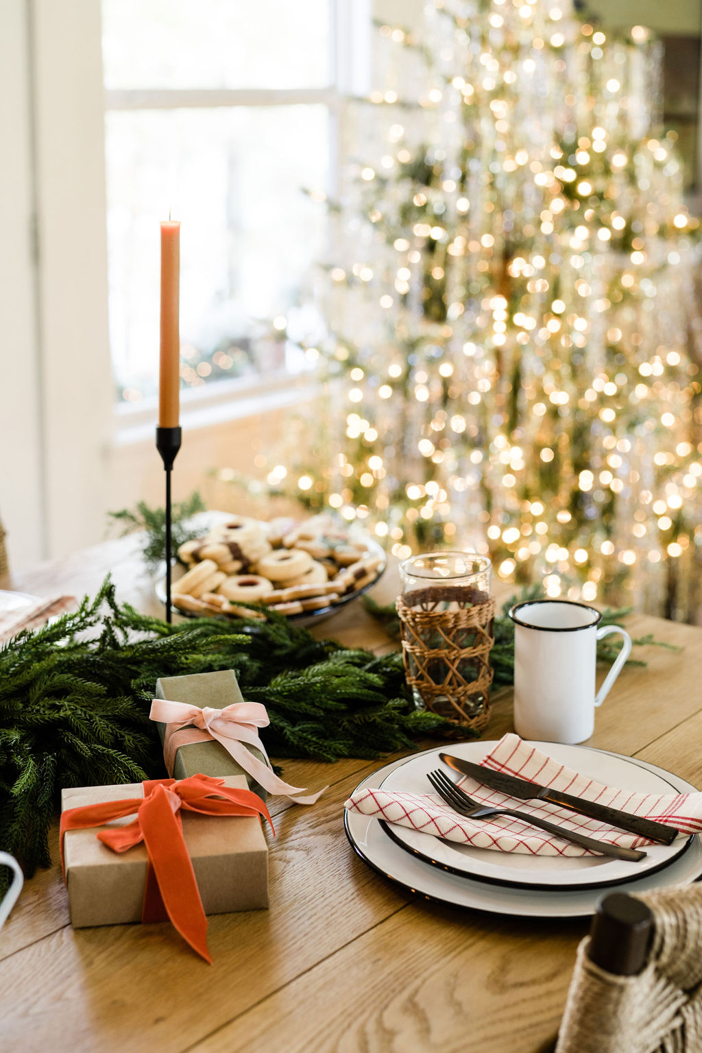 holiday table styling with taper candles and gingham napkins green garland centerpiece
