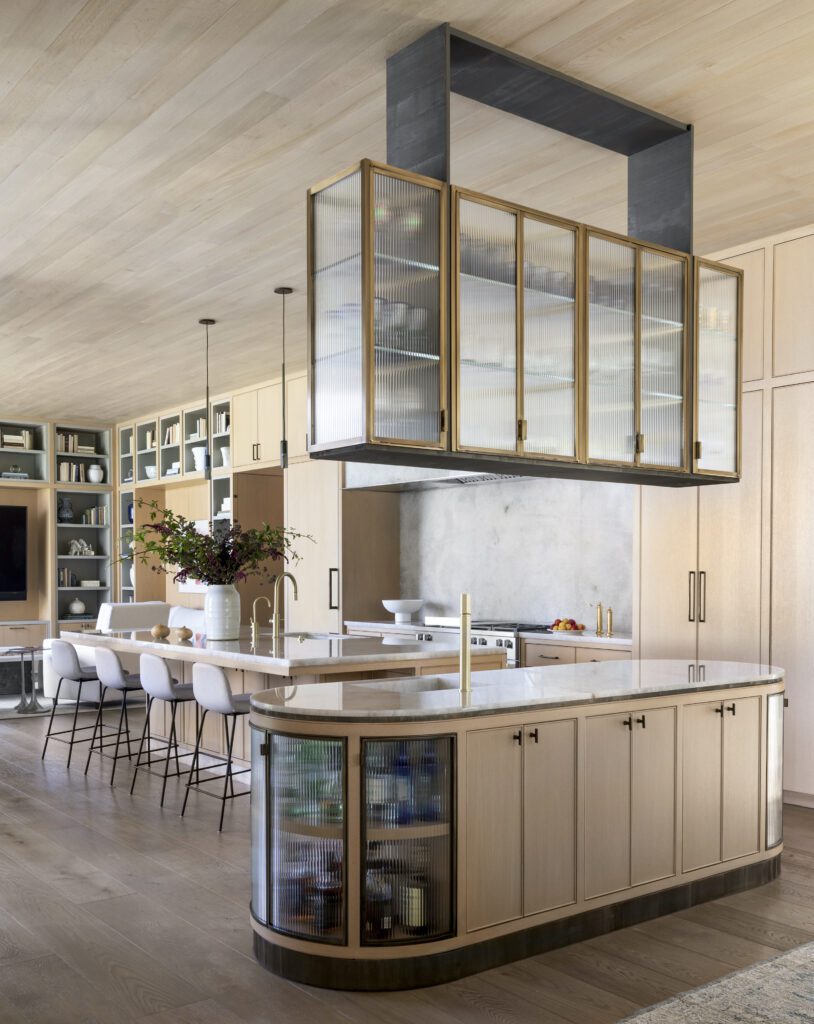 Ceiling-mounted brass and glass bar cabinet in the kitchen by Marie Flanigan Interiors