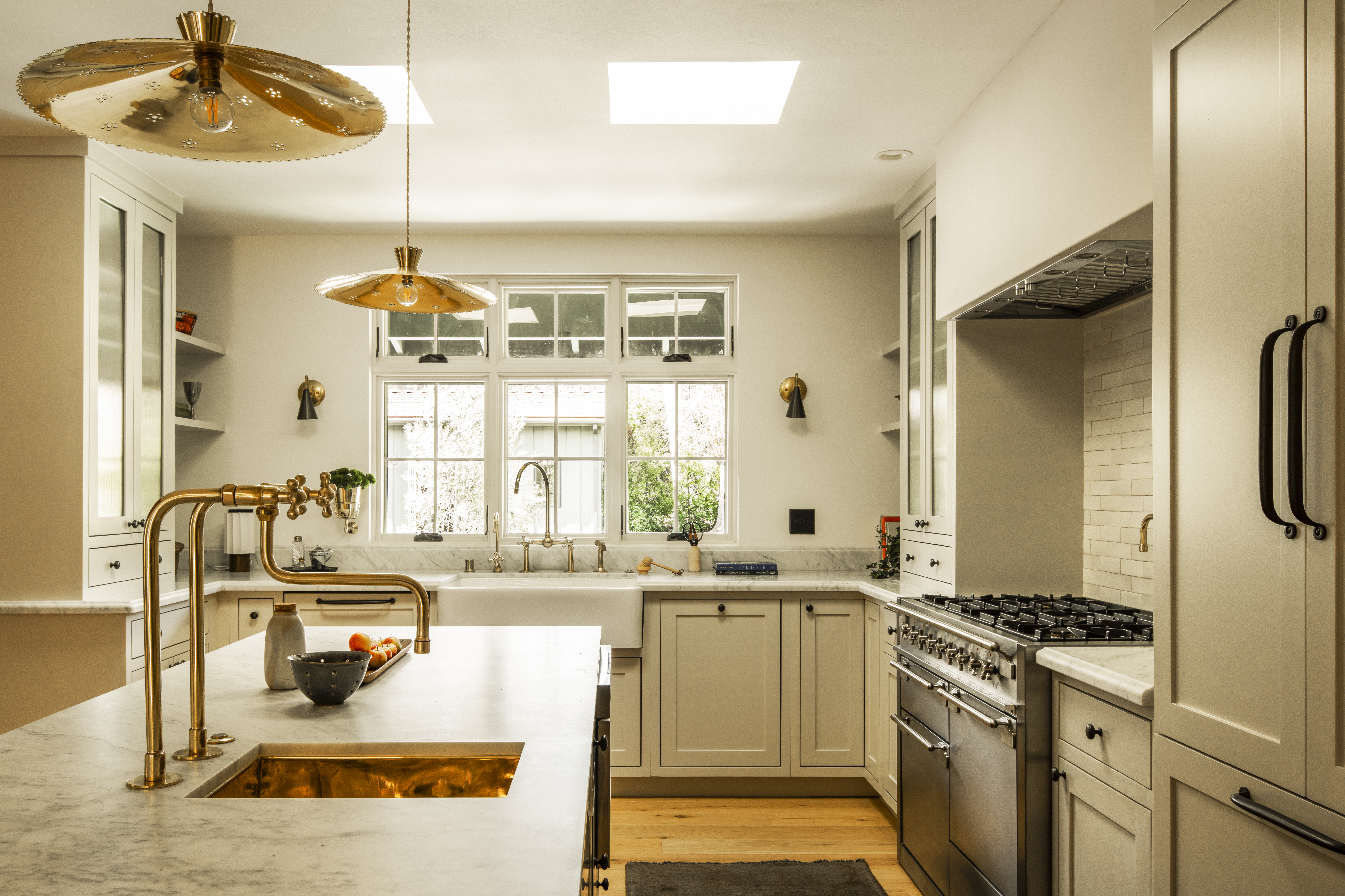 Open white kitchen design with brass fixtures