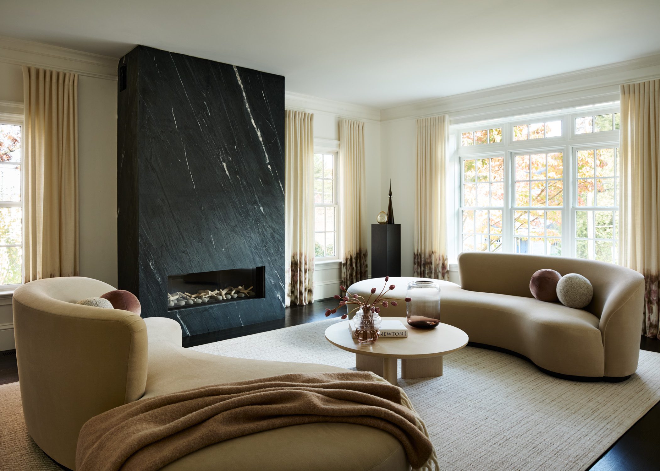 Living room with sculptural seating and black marble fireplace