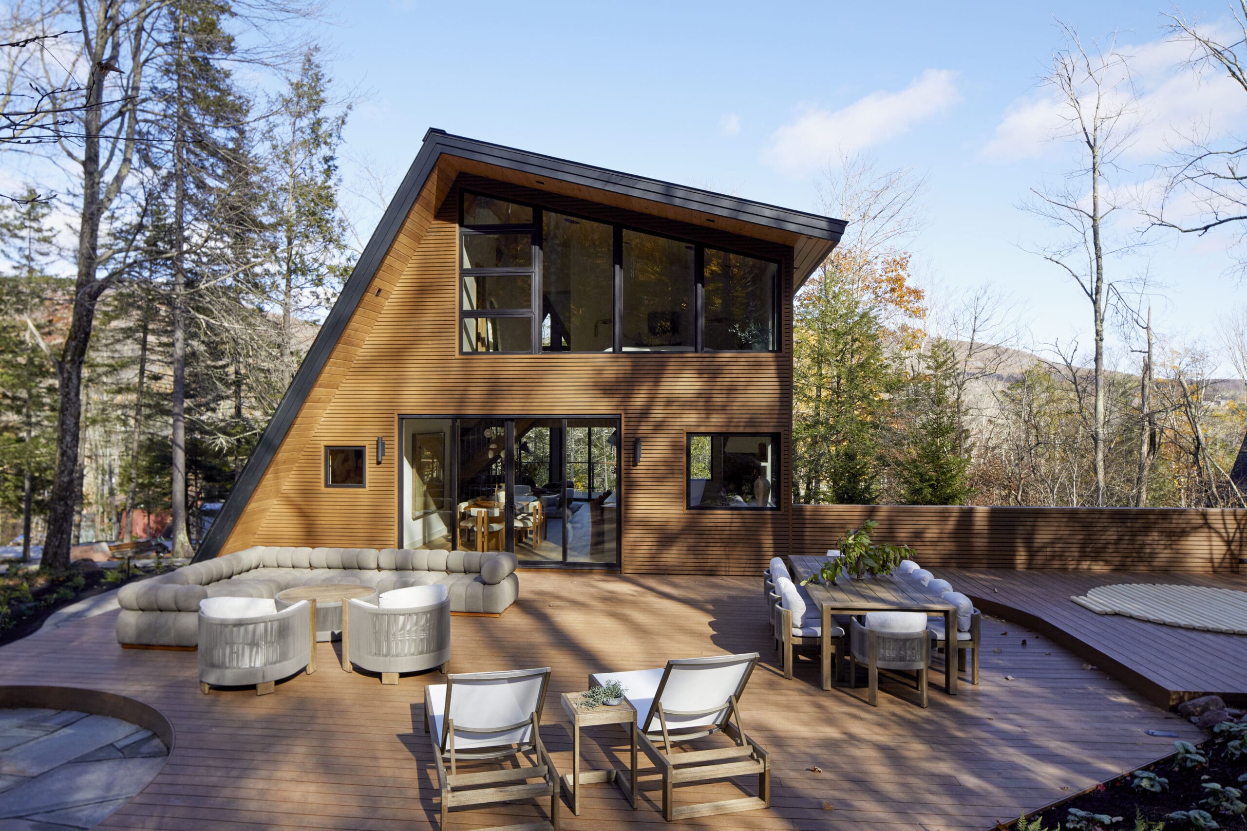 Exterior A-frame cabin with dining table and lounge chairs