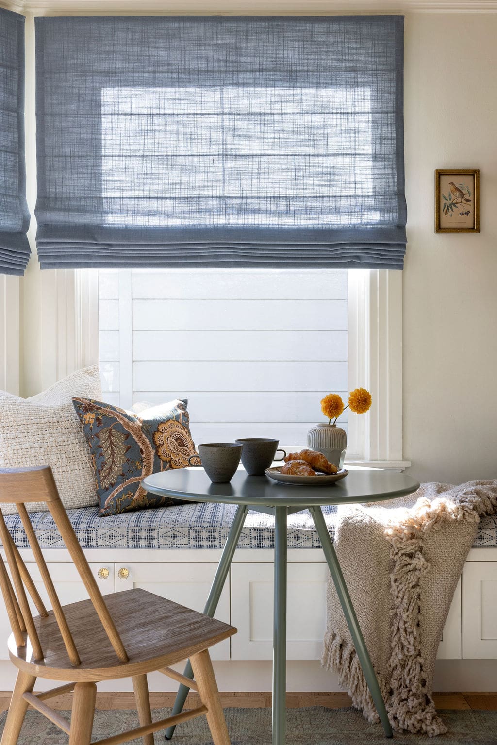 Window dining nook with blue roman shades