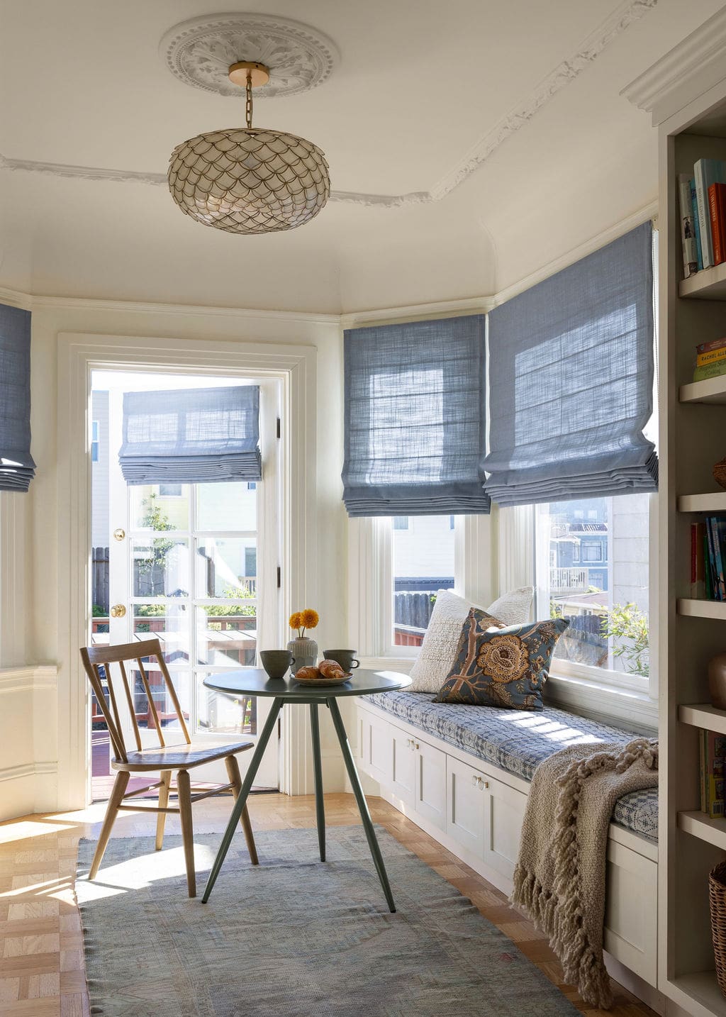 Window dining nook with blue roman shades