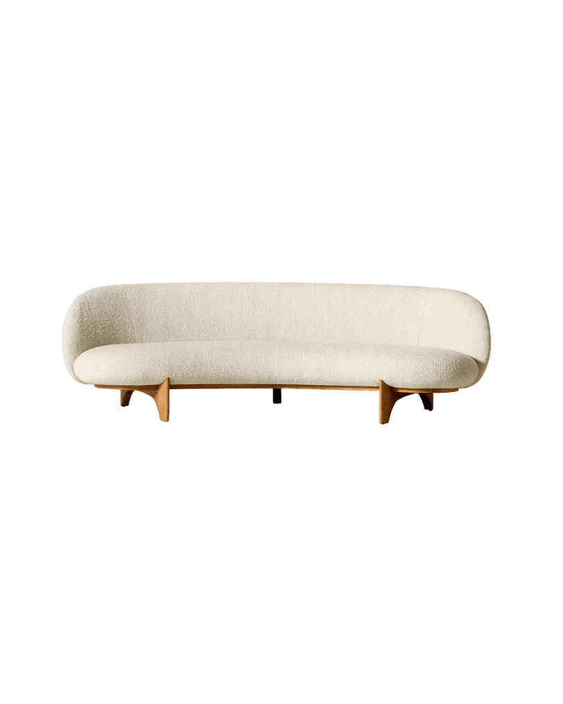 Cream boucle sofa with curved back and wooden legs on a green background