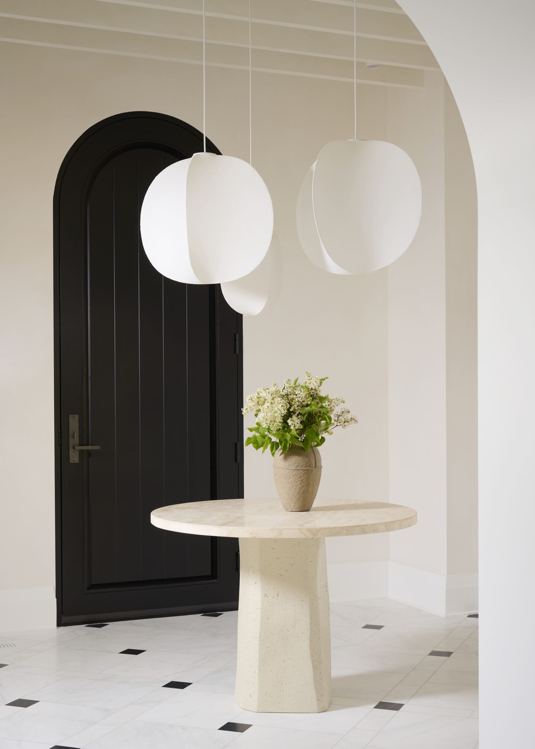 White entryway with white pendant lights black door