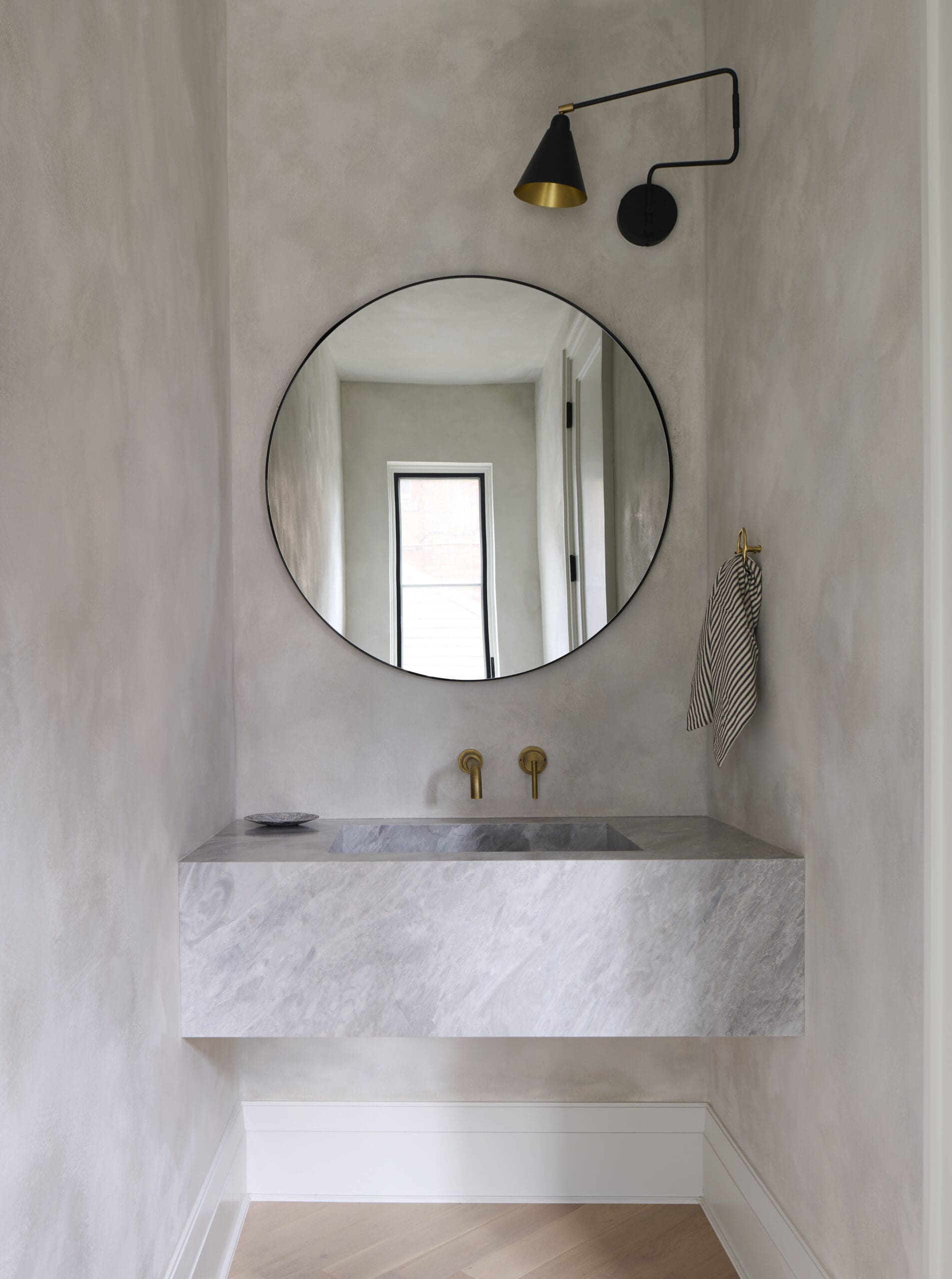 Stone bathroom with circular mirror