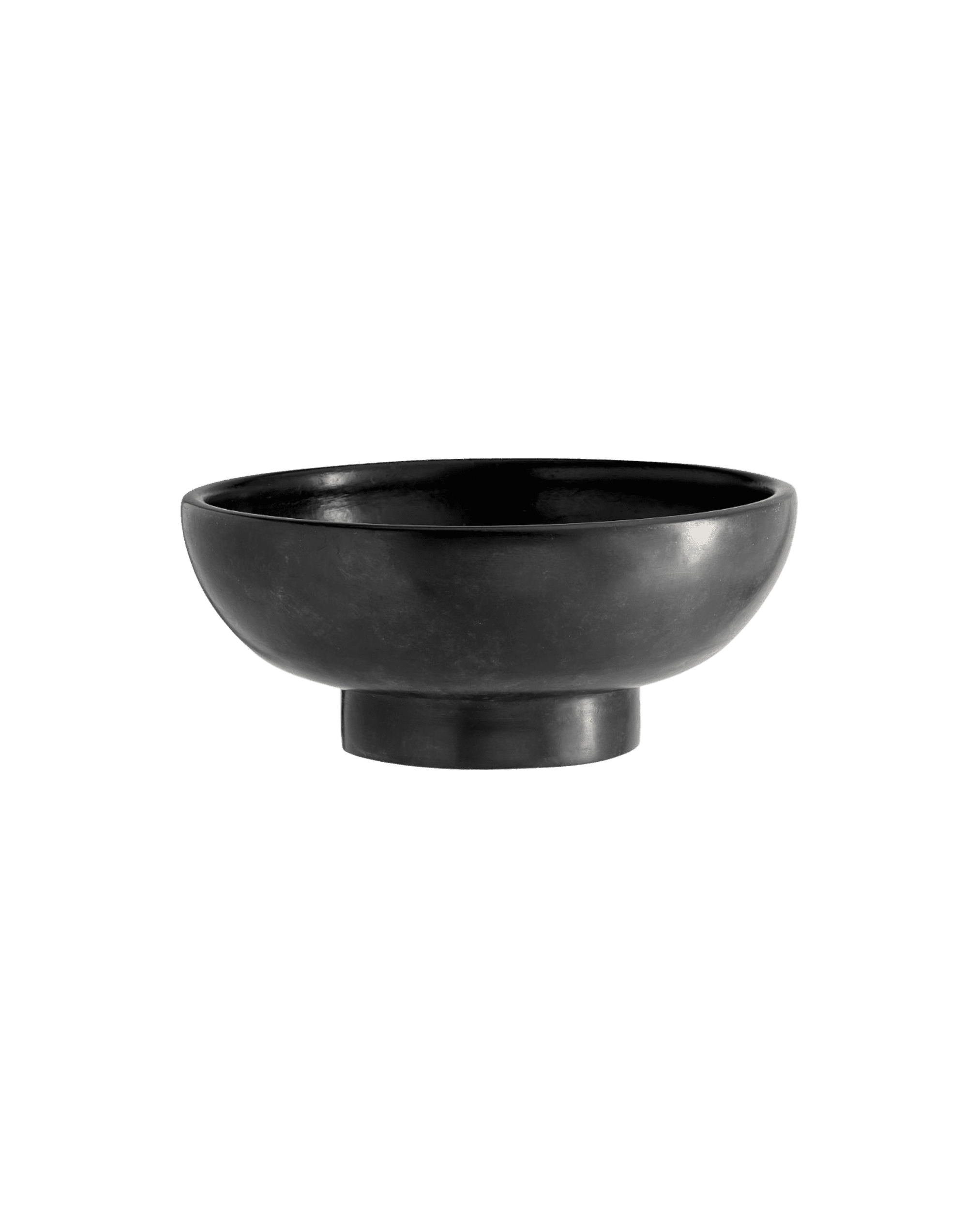 Black ceramic bowl on a short pedestal against a black background, rim visible.