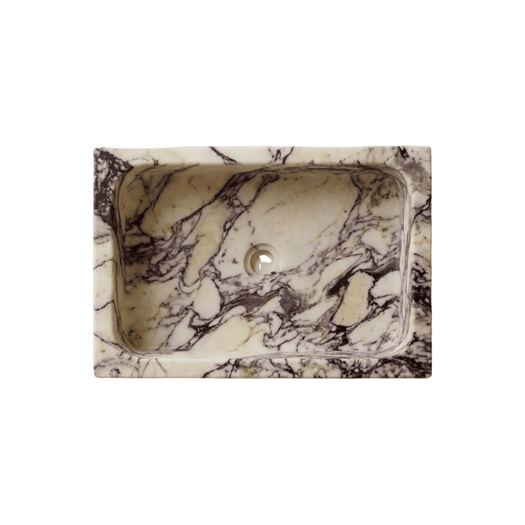Rectangular marble sink with bold veining in cream and black tones, set against a green background.