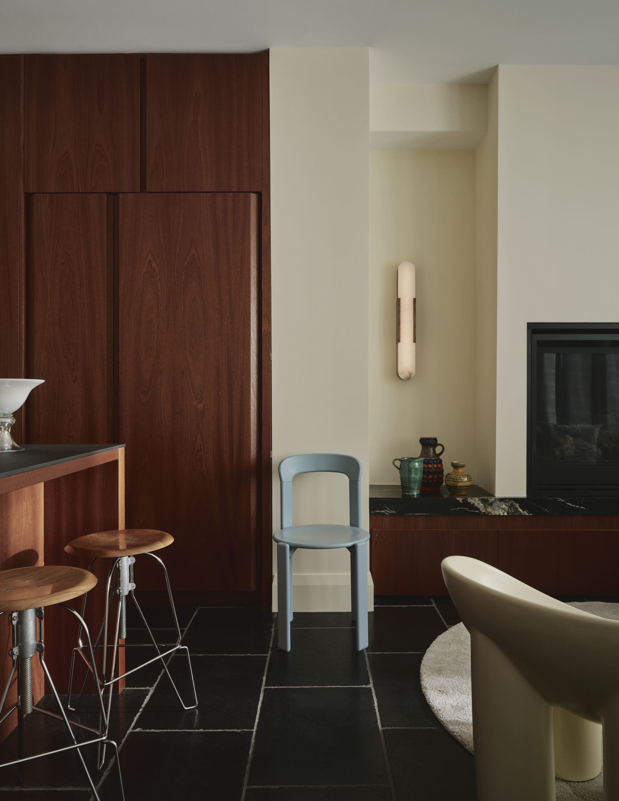 Contemporary kitchen nook with dark wood cabinets, pale walls, and a blue chair by a countertop.