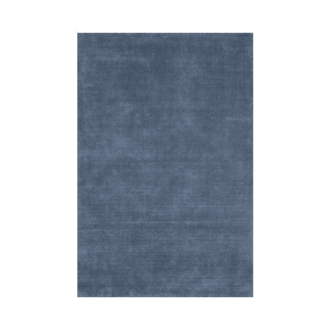 Blue textured area rug with a worn denim-like finish against a green background at center.