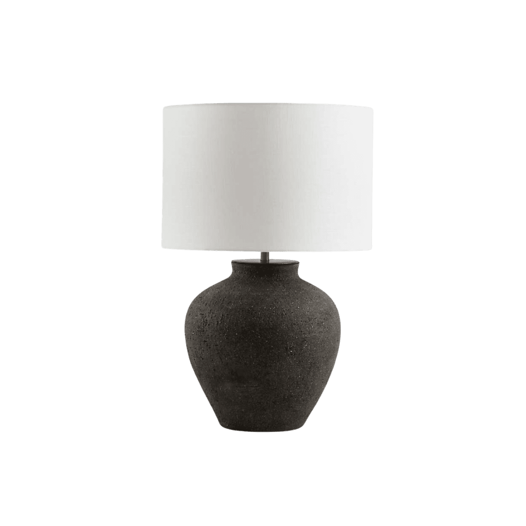 Table lamp with a dark, speckled ceramic base and a white cylindrical lampshade