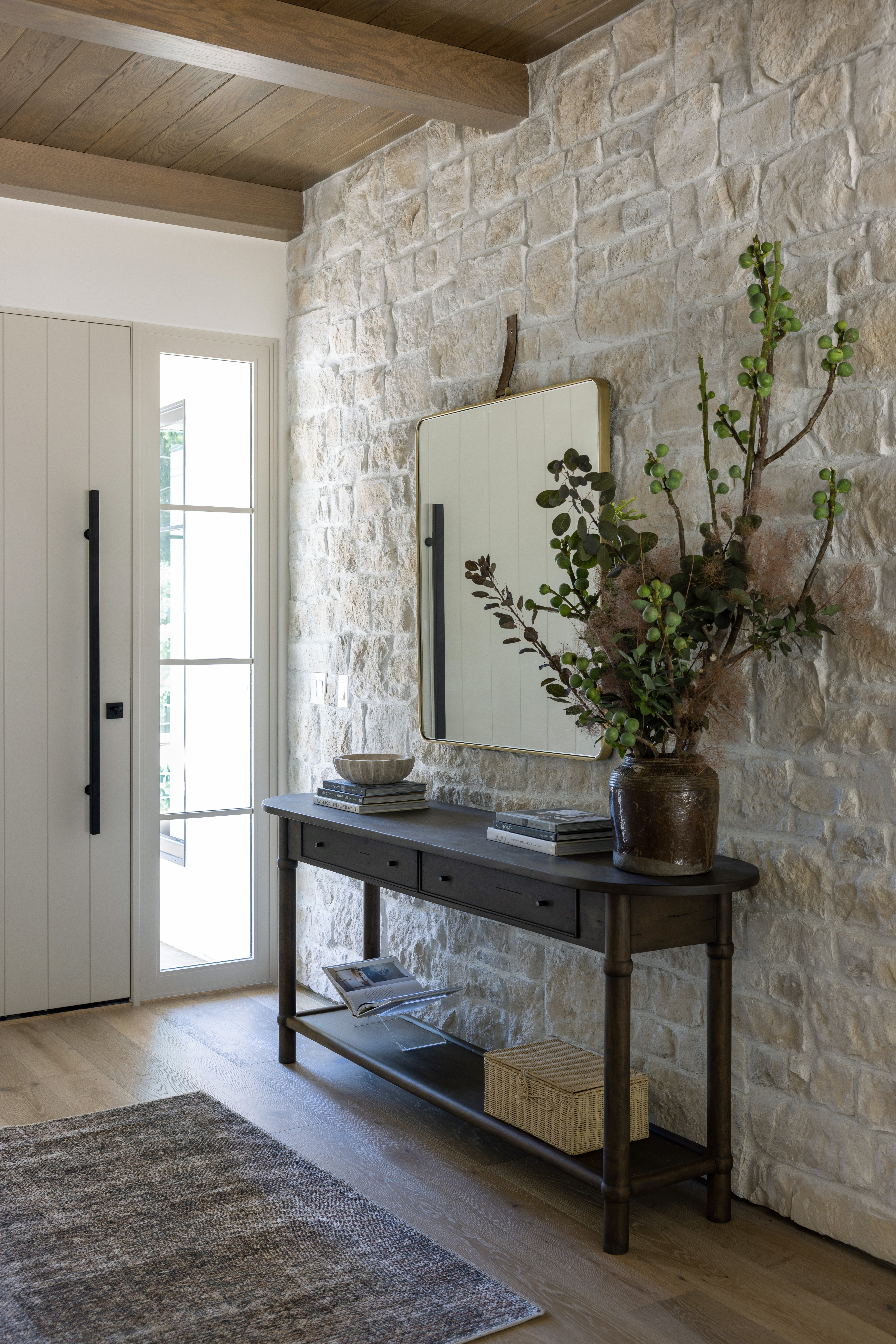 Stone wall with entryway table and leather mirror