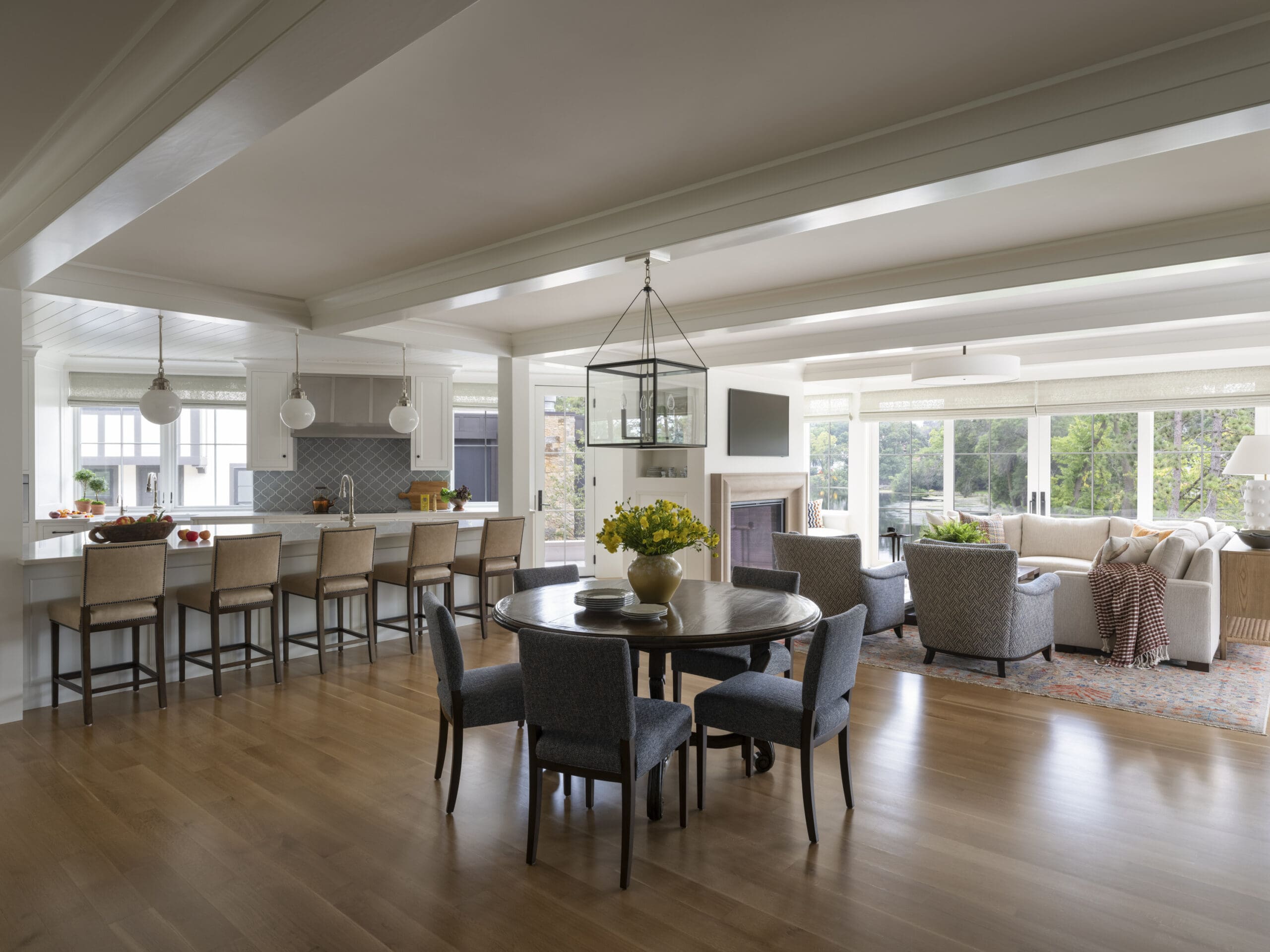 Open-concept kitchen and living room with a white island, pendant lights, and large windows filled with natural light.