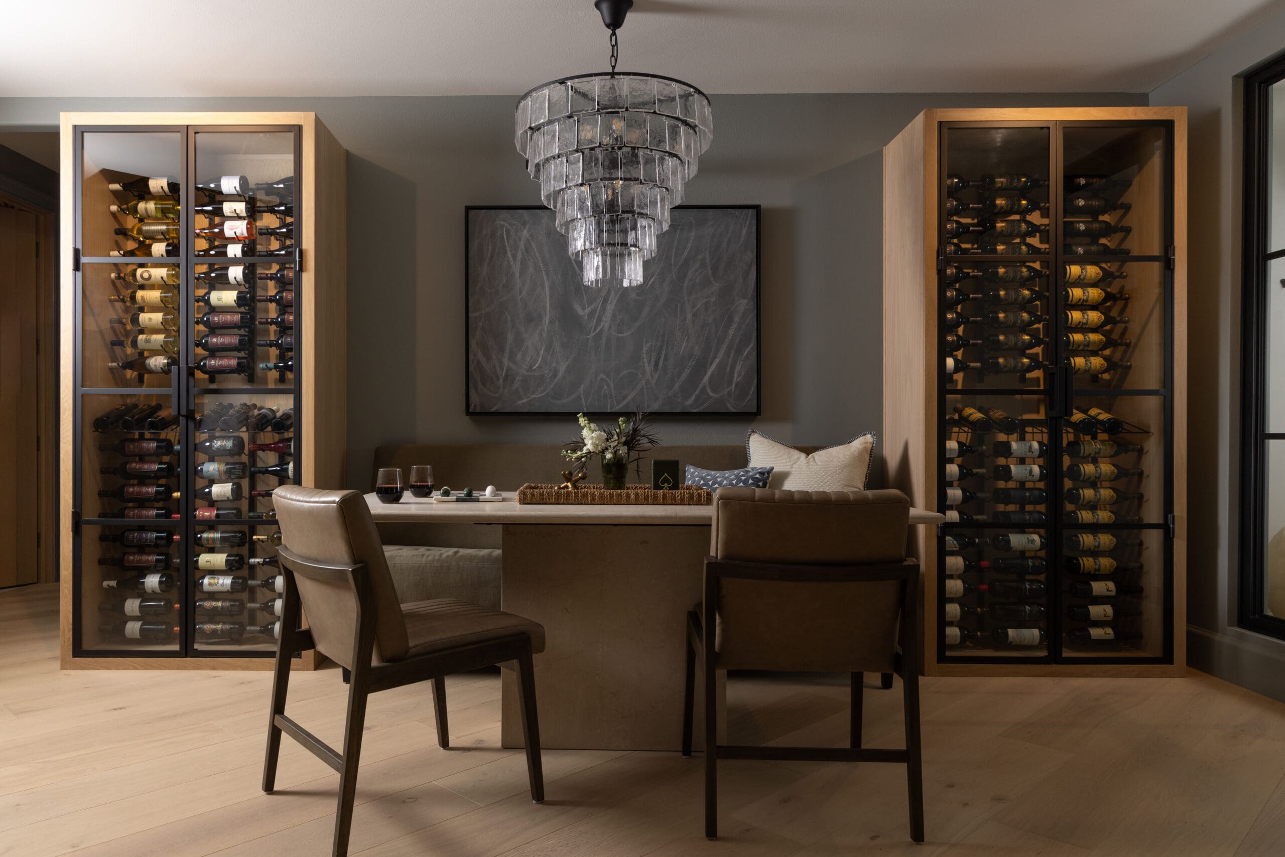 Modern dining area with glass-front wine storage cabinets flanking a central table and chandelier?