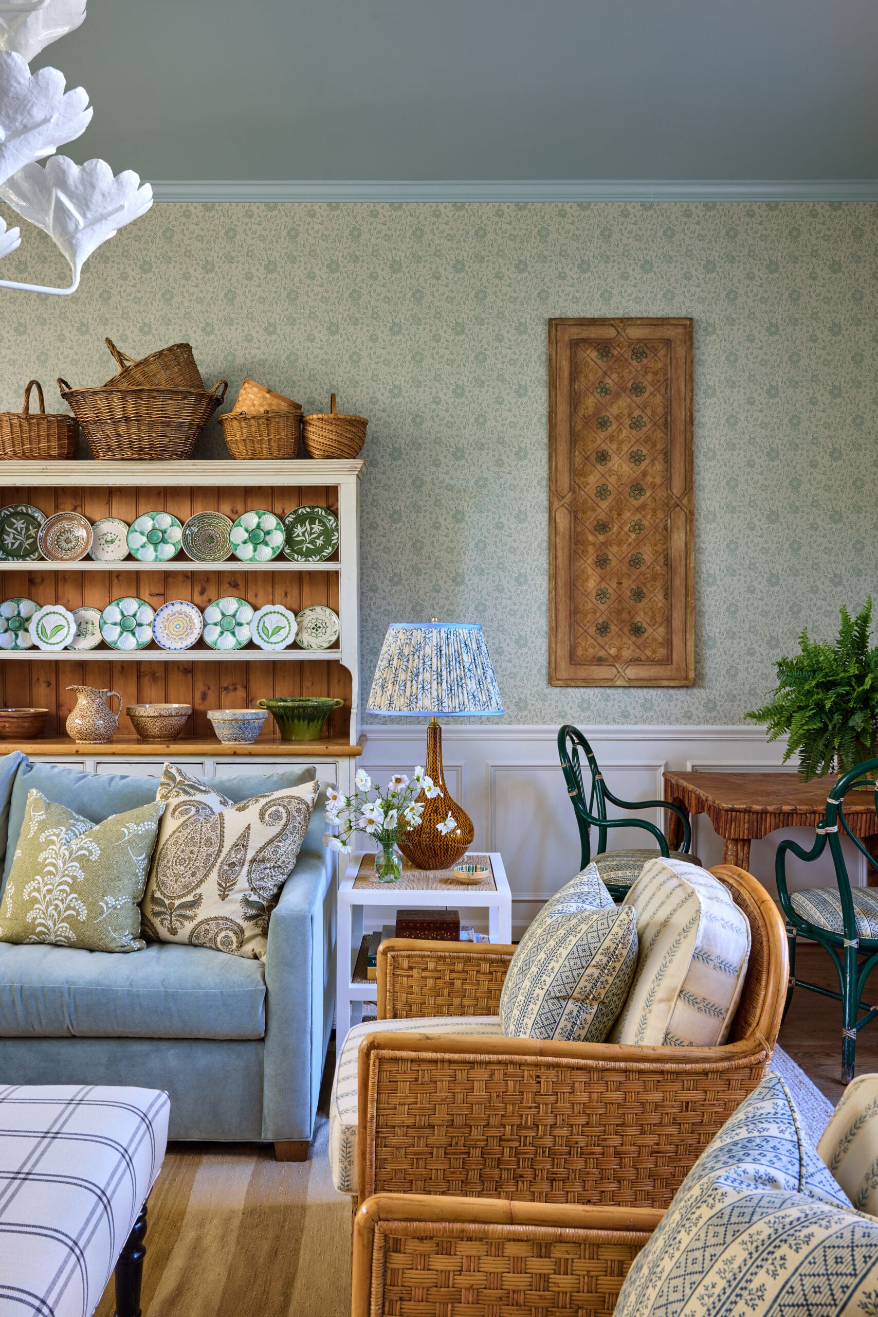 Cozy living room corner with a white china cabinet displaying green and white decorative plates and wicker baskets on top.