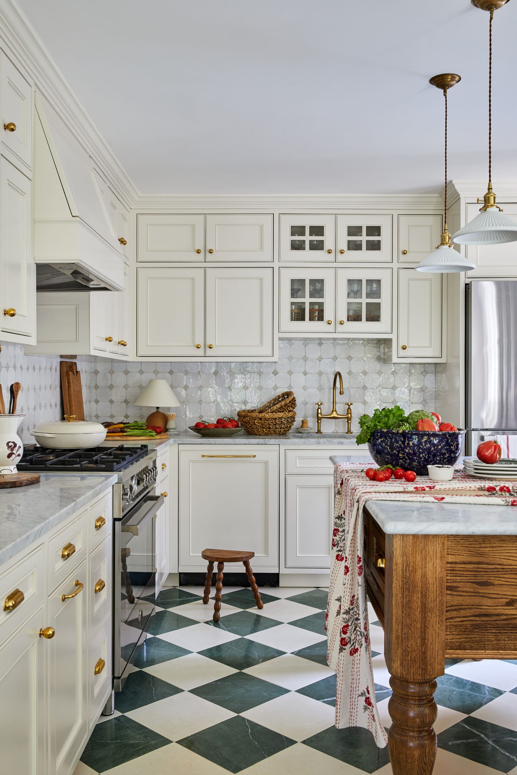 Bright white kitchen with glass-front and solid cabinets, brass knobs, and a green-and-white checkered floor.