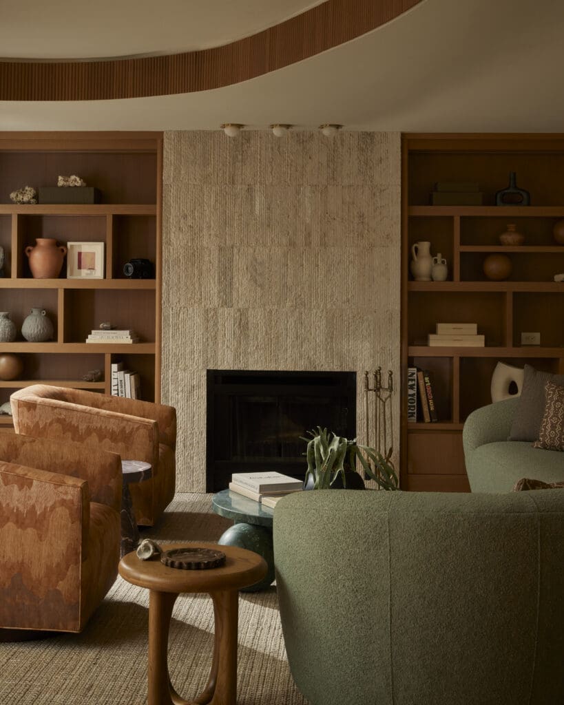 Cozy living room with a stone fireplace framed by wooden bookshelves and a green sofa nearby.