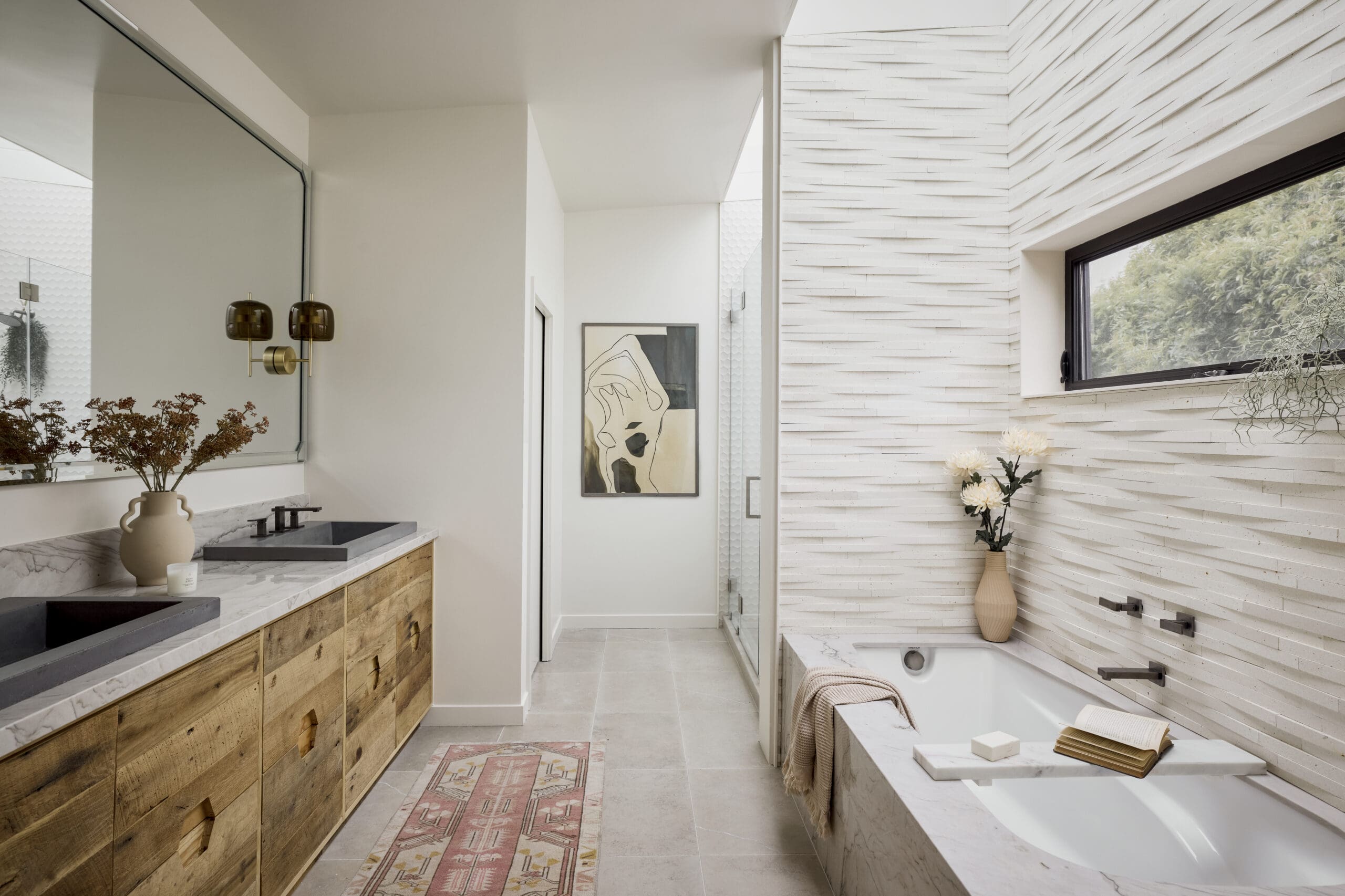 Modern bathroom with white marble countertops, wooden vanity cabinets, and dual sinks; decorative vase and wall art nearby.