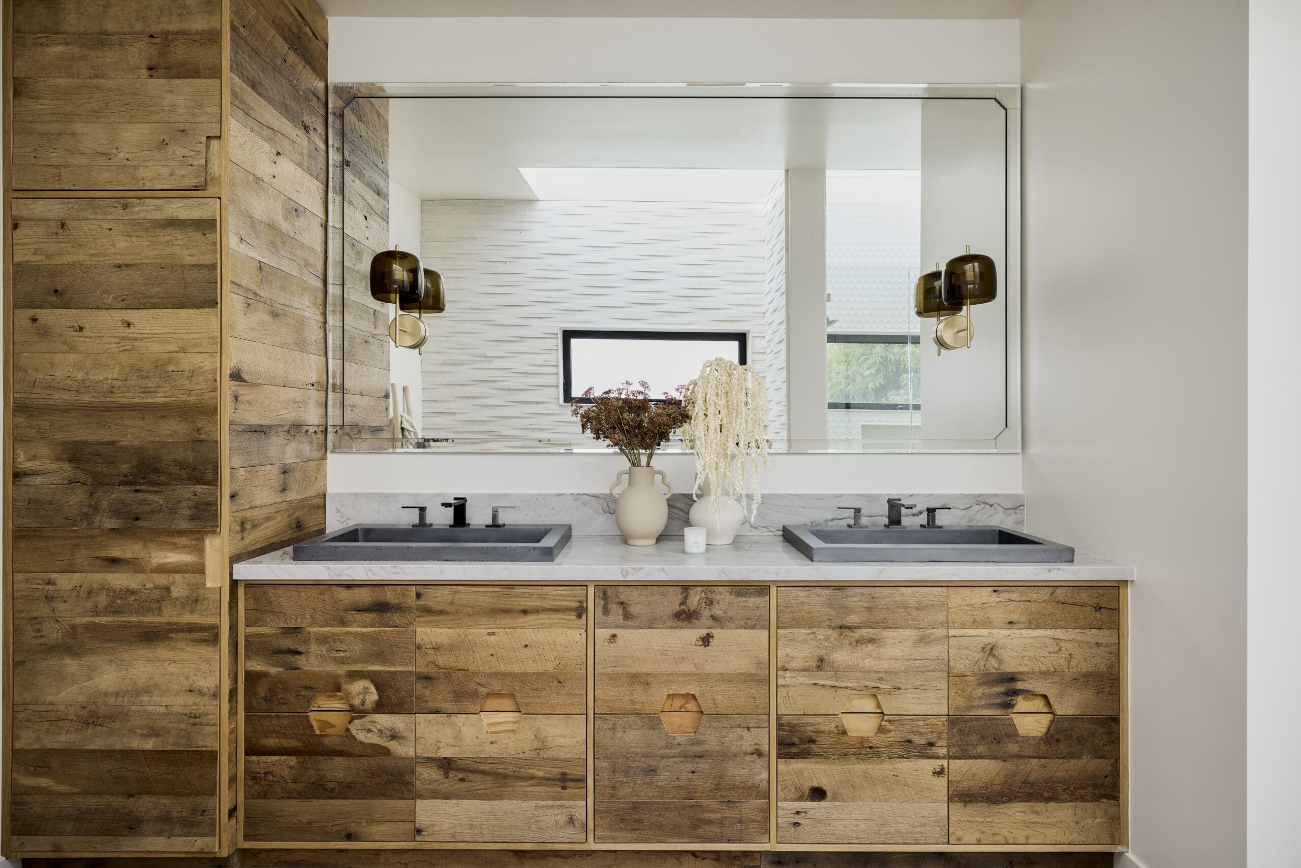 Double-sink bathroom vanity with a marble countertop, wood cabinets, and a large frameless mirror.