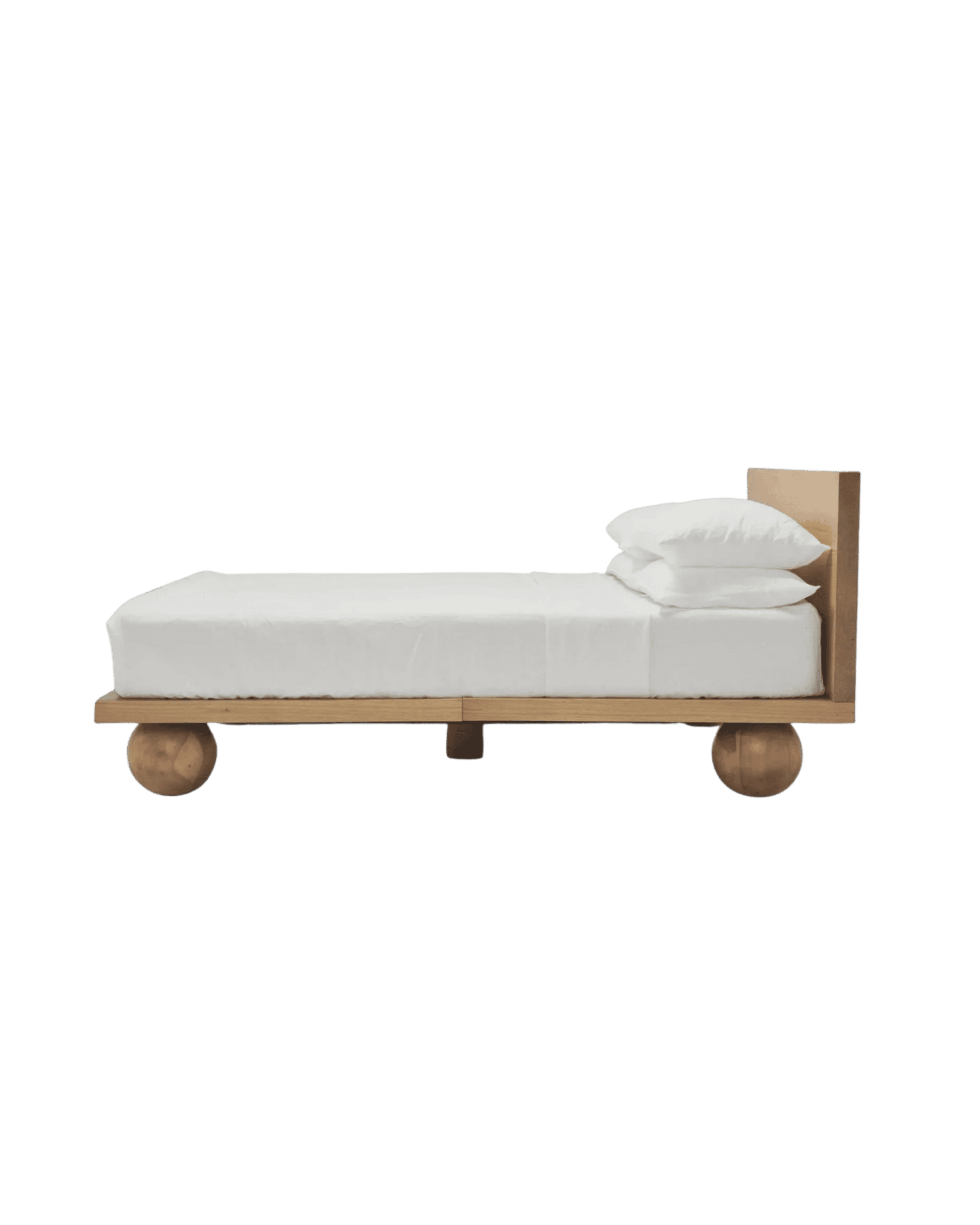 Low wooden platform bed with a white mattress and pillows on wheels, set against a black background.