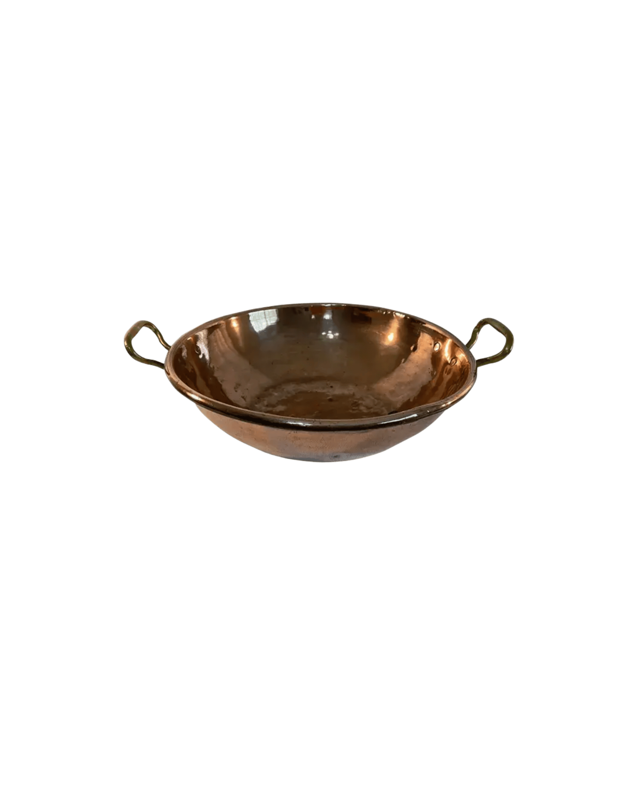 Copper frying pan with two brass handles against a black background, viewed from above edges in frame.