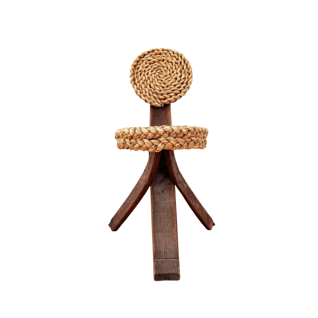 Rustic wooden stick figure with a woven circular head and rope belt on a green background, arms made of curved wood pieces.