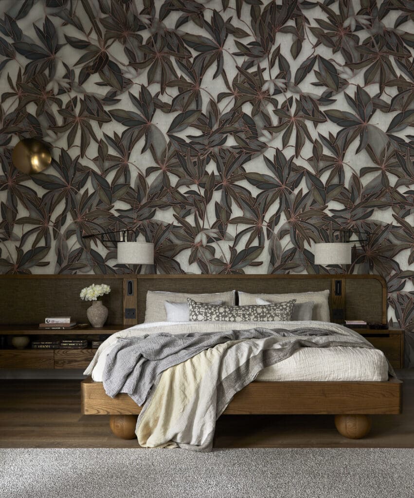 Bedroom with a dark botanical wallpaper, a low wooden platform bed, and layered beige-gray linens.