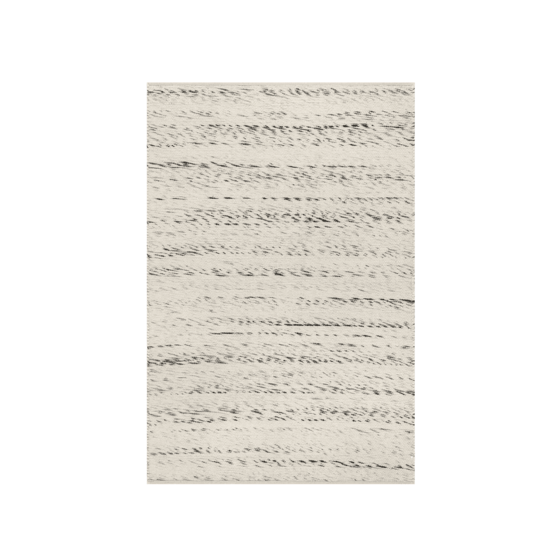 Cream rug with horizontal black wavy lines laid on a green background, flat view.