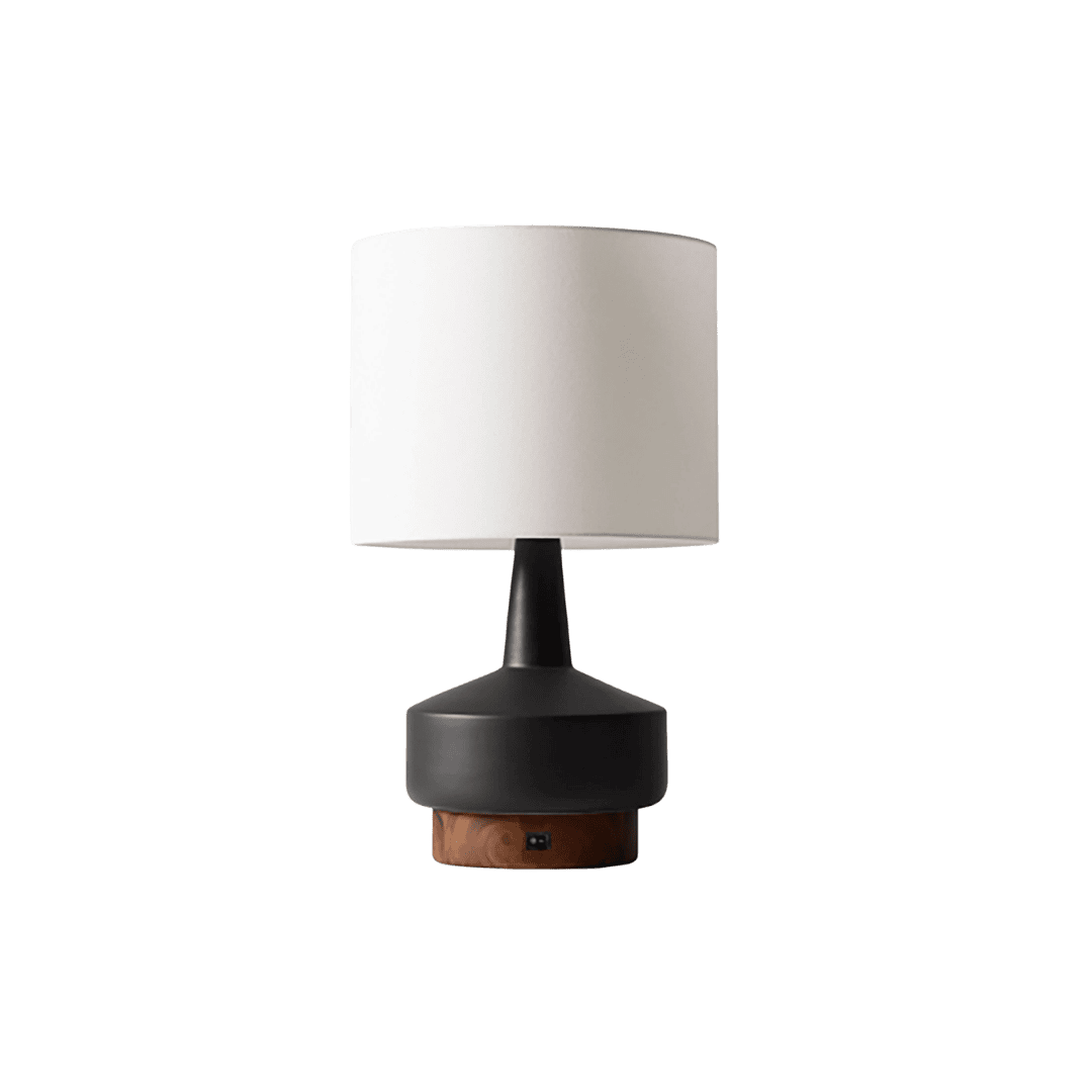 Modern table lamp with a white cylindrical shade, black stem, and a wood-accented base on a green background.
